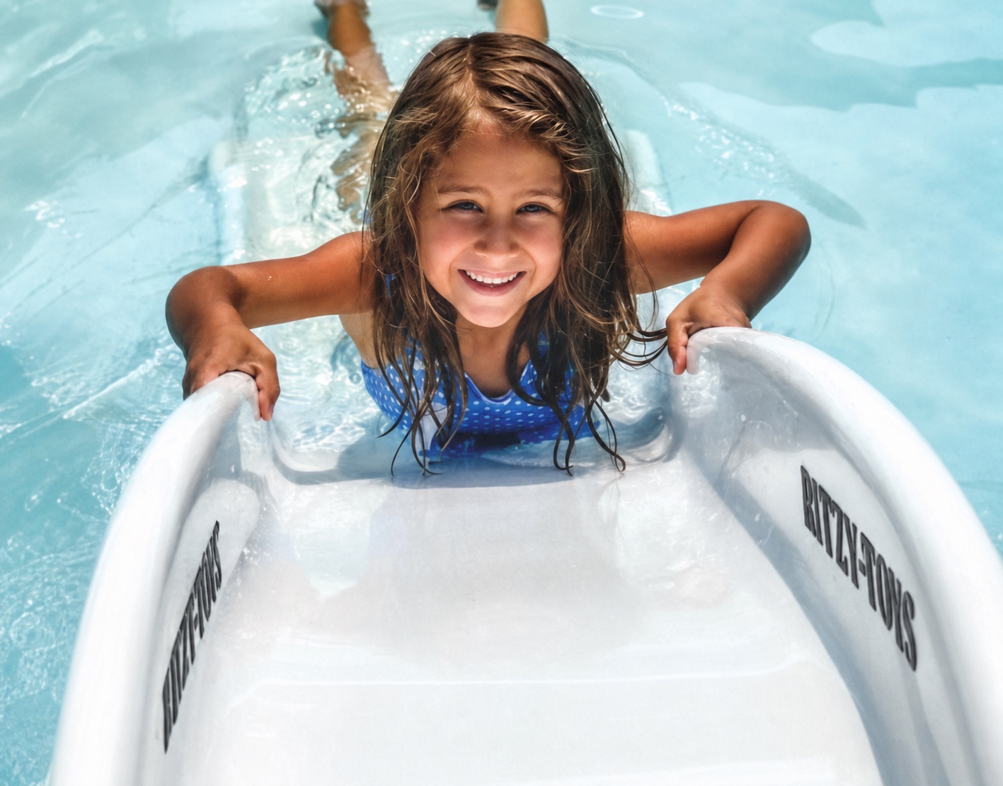 A child enjoying the Ritzy-Slide beside a swimming pool